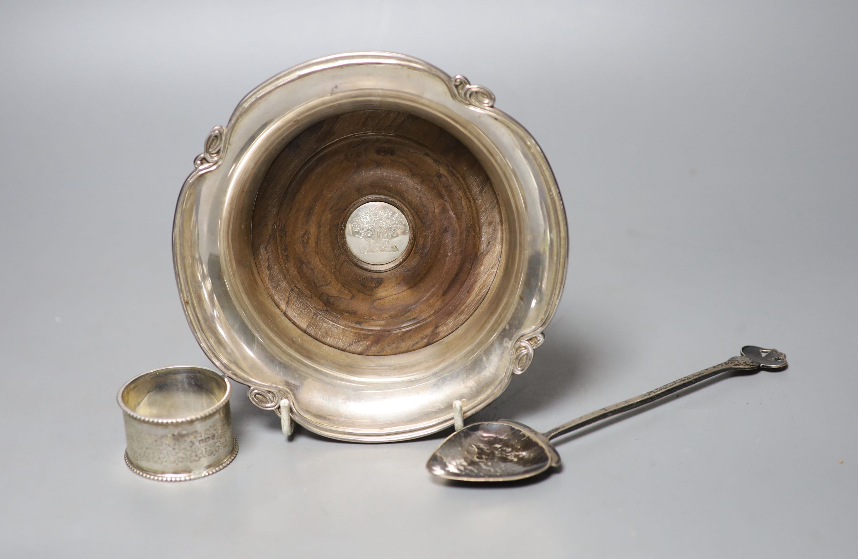 A George V Art Nouveau silver spoon, D & M Davis, Birmingham, 1911, 18.2cm, together with a modern silver mounted wine coaster and a silver napkin ring.